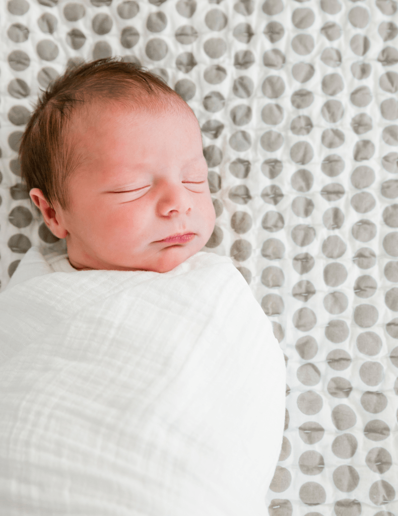 sleeping baby swaddled showing one of the key elements of newborn sleep shaping
