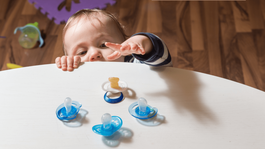 Baby reaching to grab pacifier, practicing self-soothing skills for independent sleep