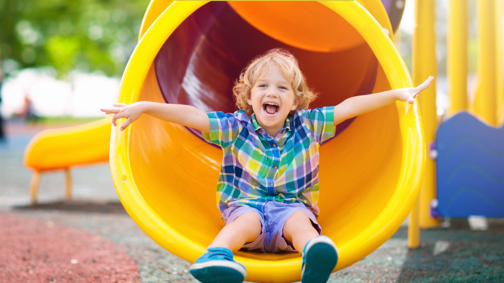 Smiling toddler at the bottom of a slide, representing active play, which leads to better sleep.